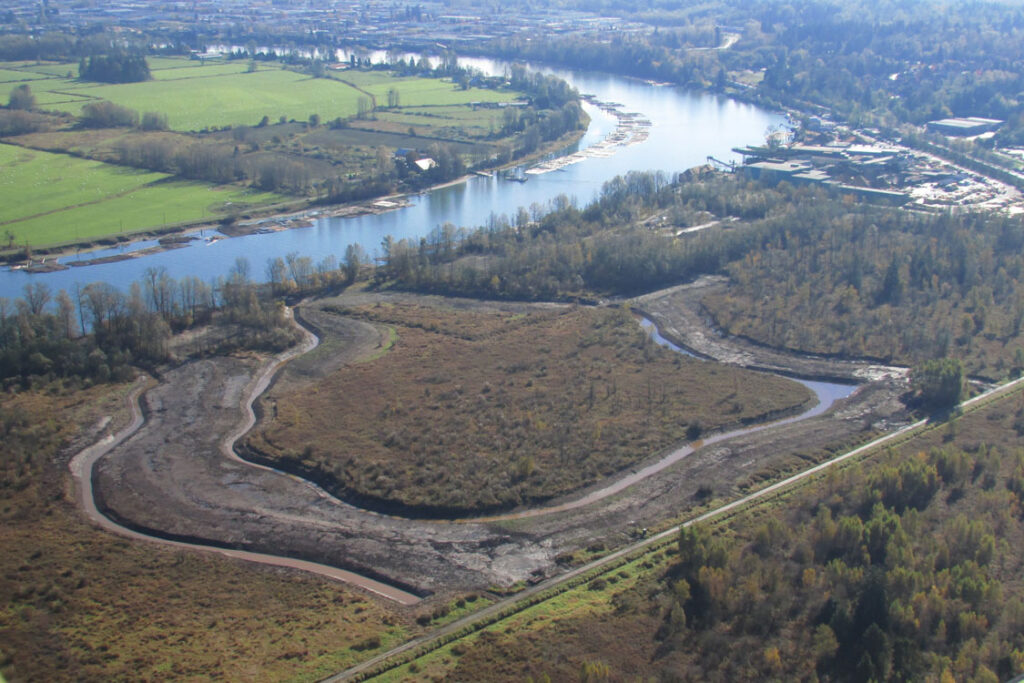 An aerial view of a river and a dirt field.