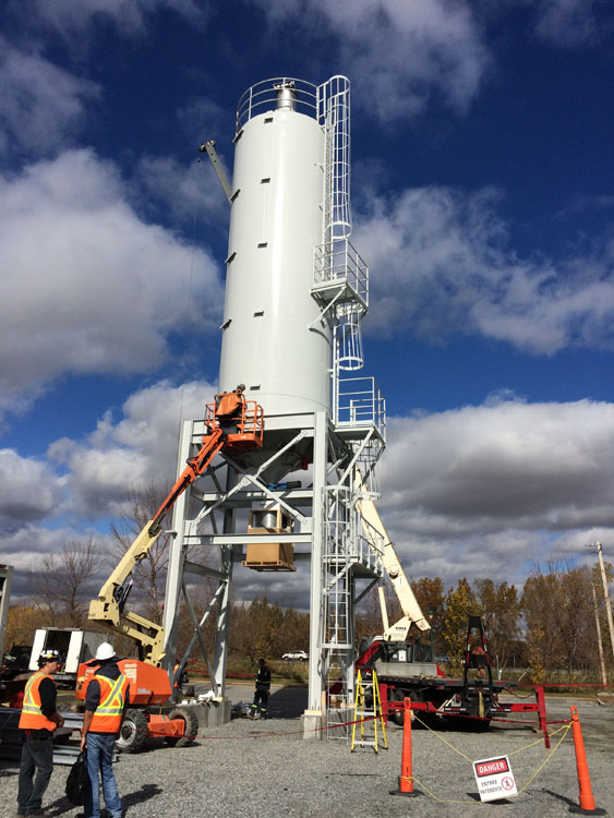 A construction crew is working on a large concrete mixer.