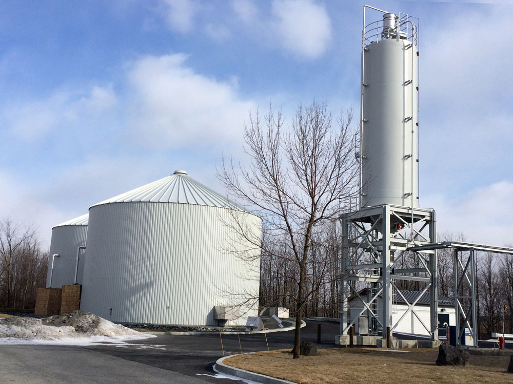 A large cement plant with a silo in front of it.