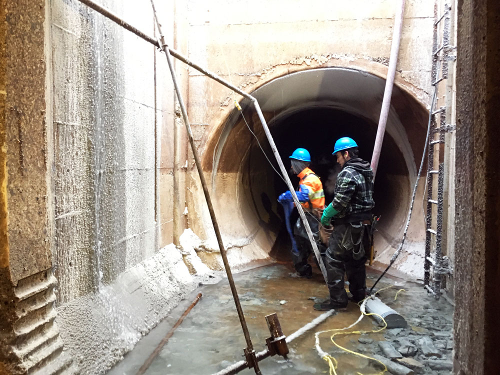 Two construction workers working in a tunnel.