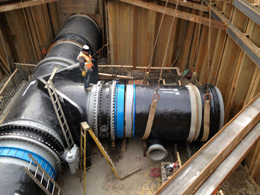 A man is working on a large pipe in a construction site.