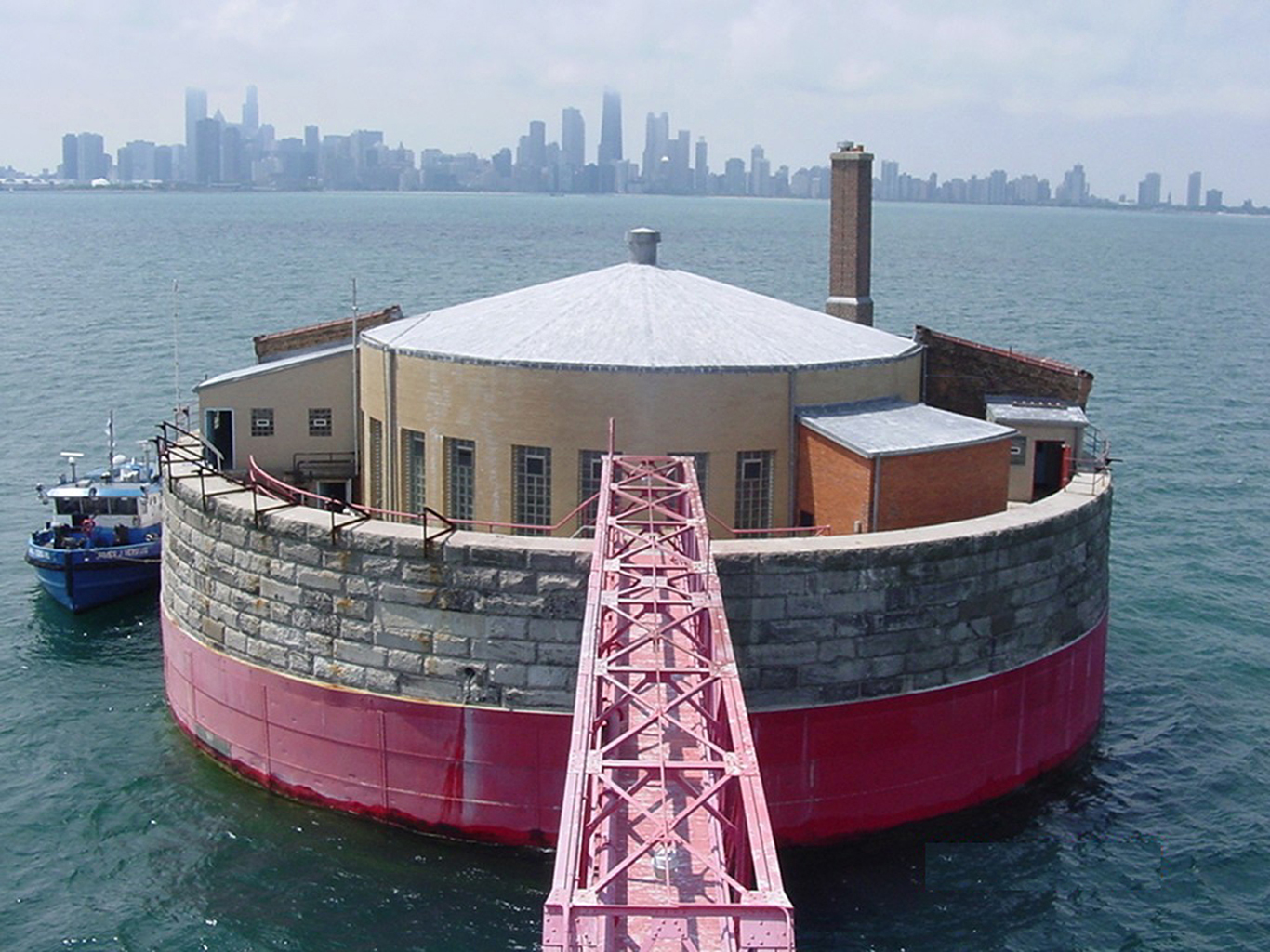 A boat is in the water next to a red building.