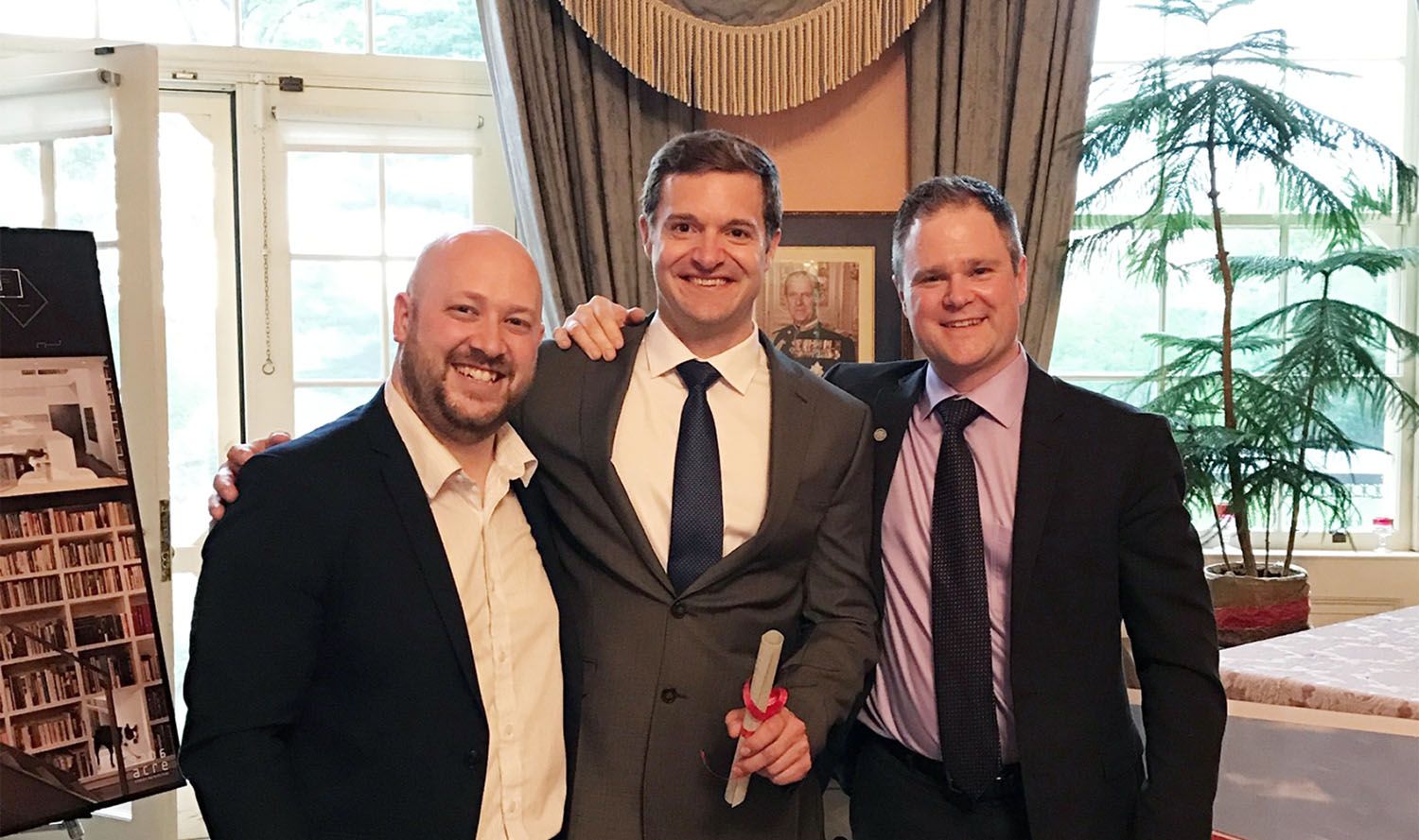 Three men in suits posing for a picture in a room.