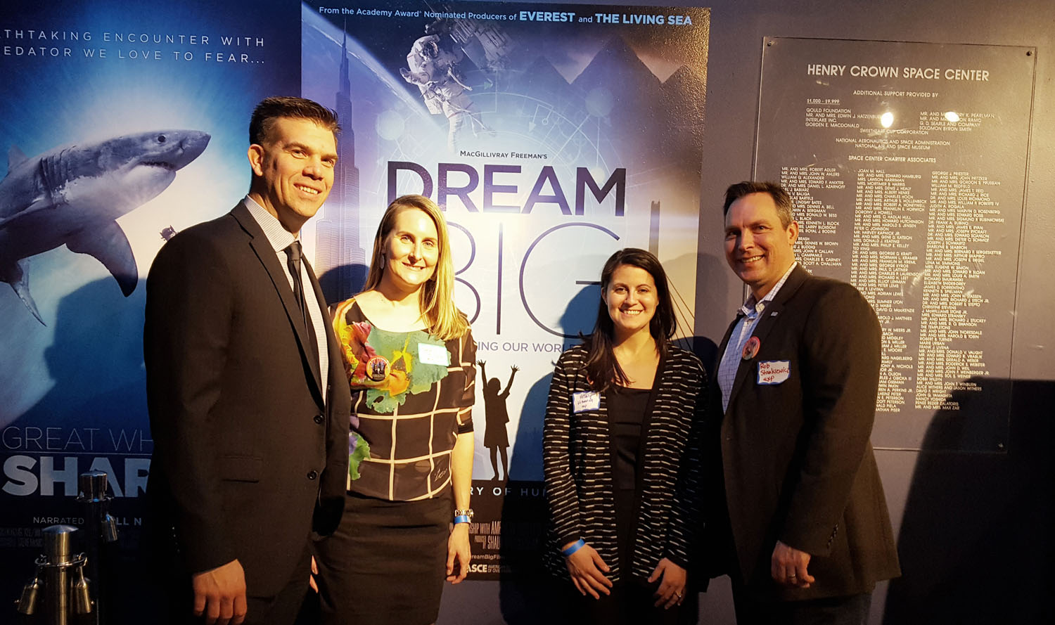 A group of people posing in front of a poster for dream big shark.