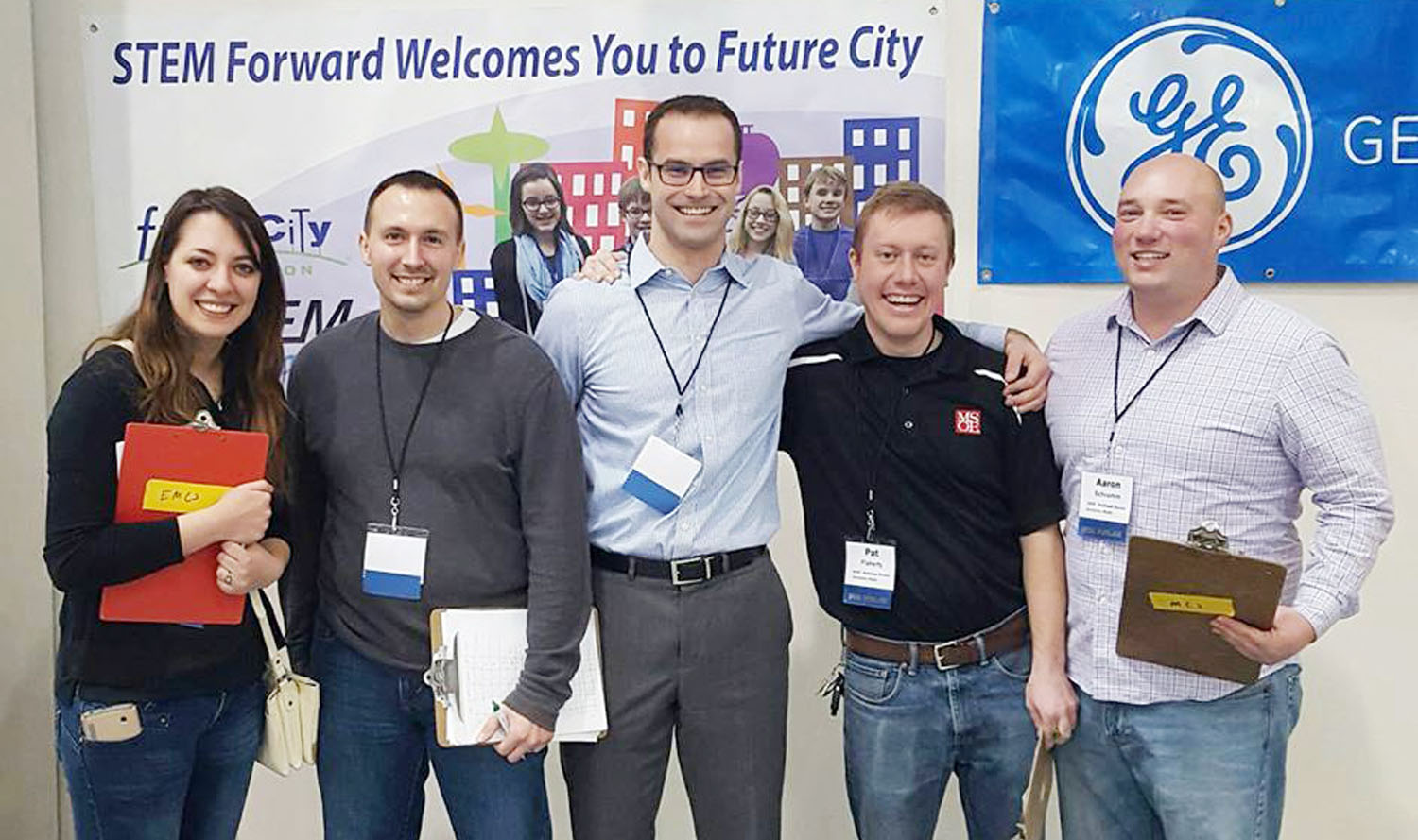 A group of people posing for a picture in front of a sign.