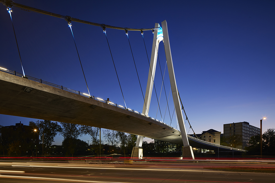 A bridge over a city street at night.