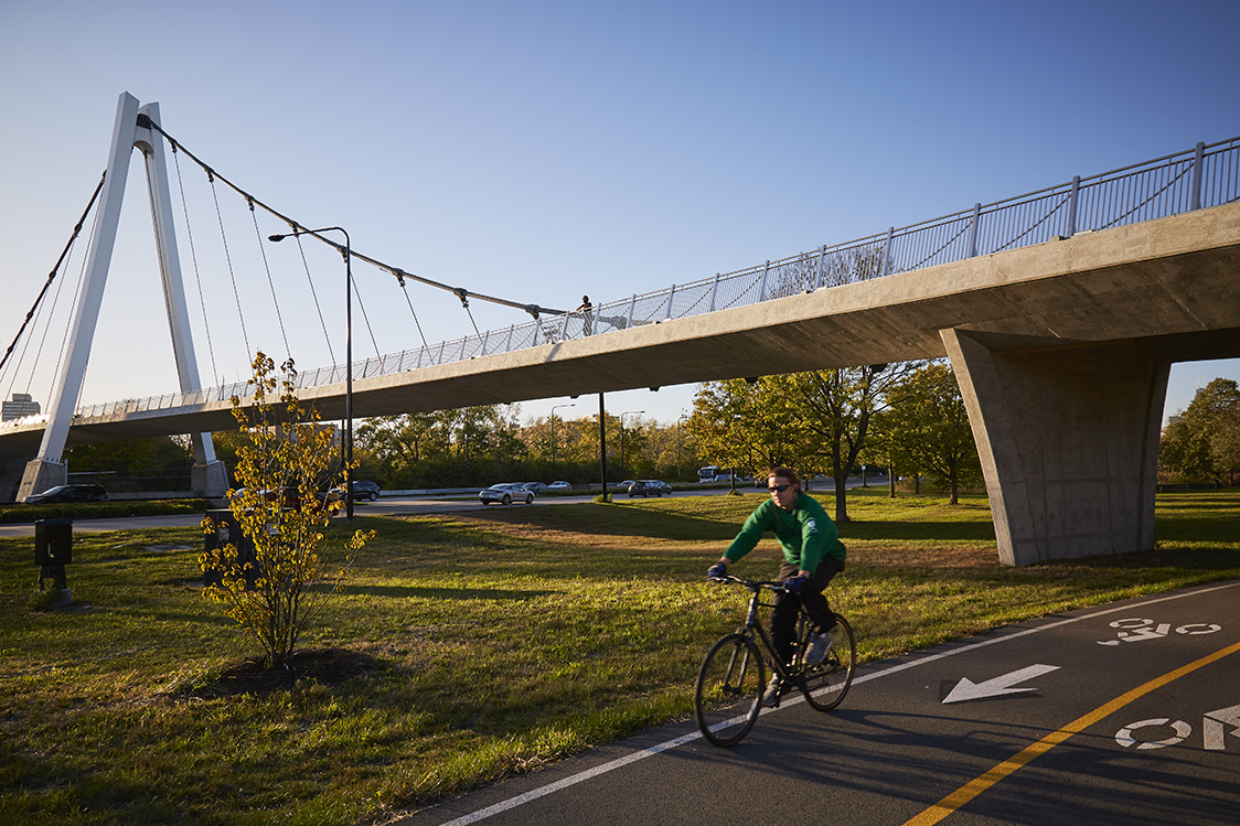 A person riding a bike under a bridge.