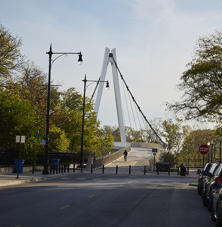 A bridge over a street with cars parked next to it.