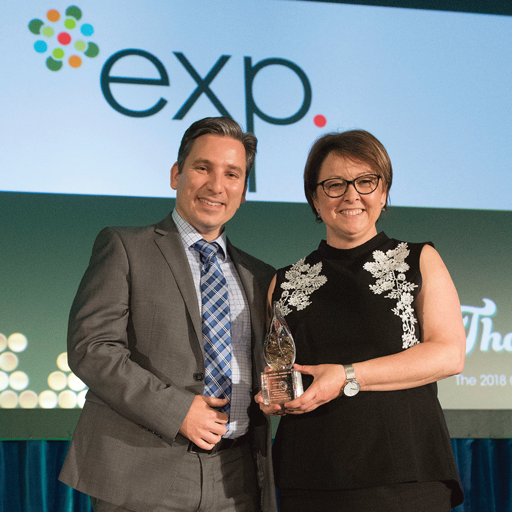 A man and woman standing in front of an exp sign.