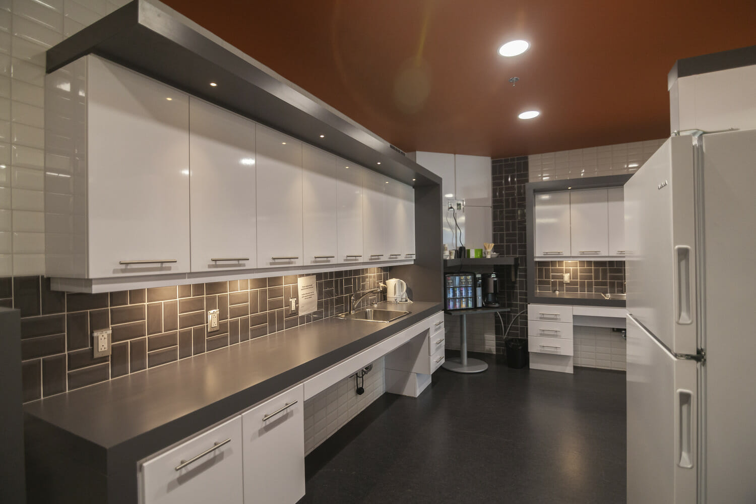 A kitchen with white cabinets and black counter tops.