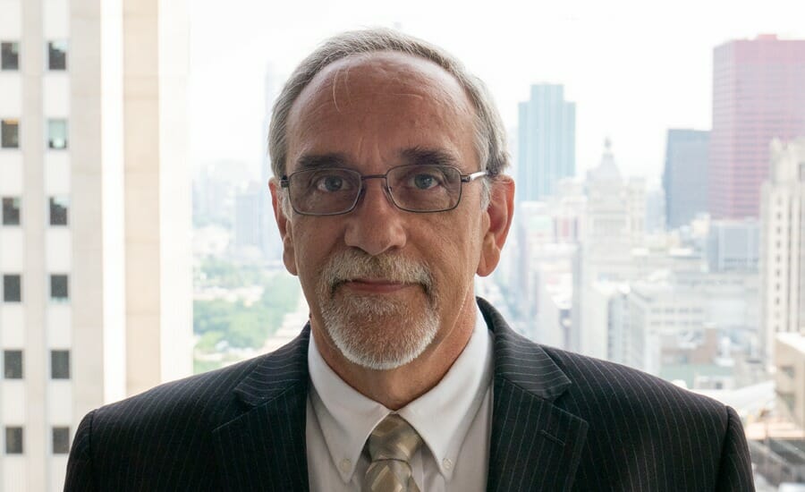 A transportation expert in a suit and tie standing in front of a city.