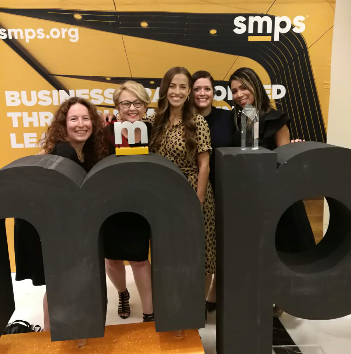 A group of women posing in front of an EXP awards sign.