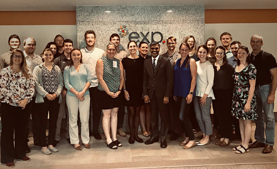 A group of EXP sustainability experts posing in front of an exo sign.