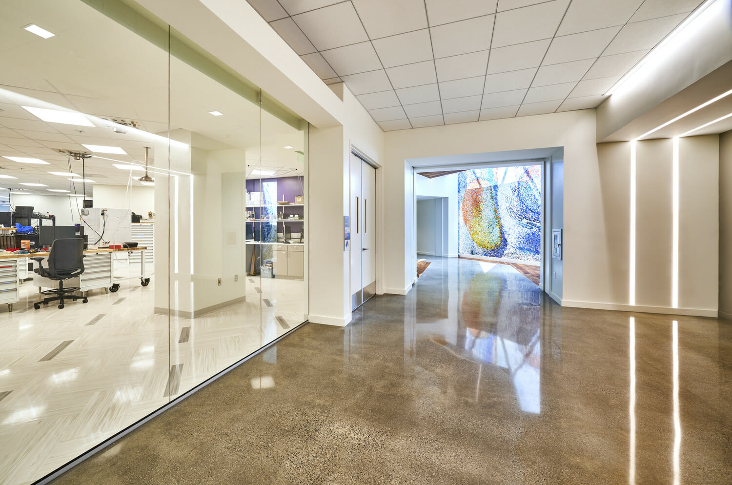 A hallway with glass walls in a medical office featuring advanced technology.