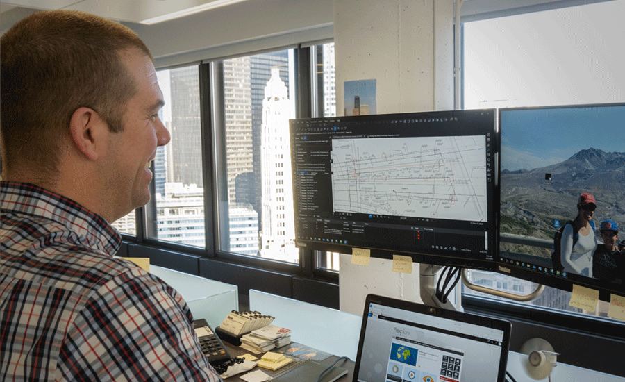 A transportation engineer analyzing a map on dual monitors.
