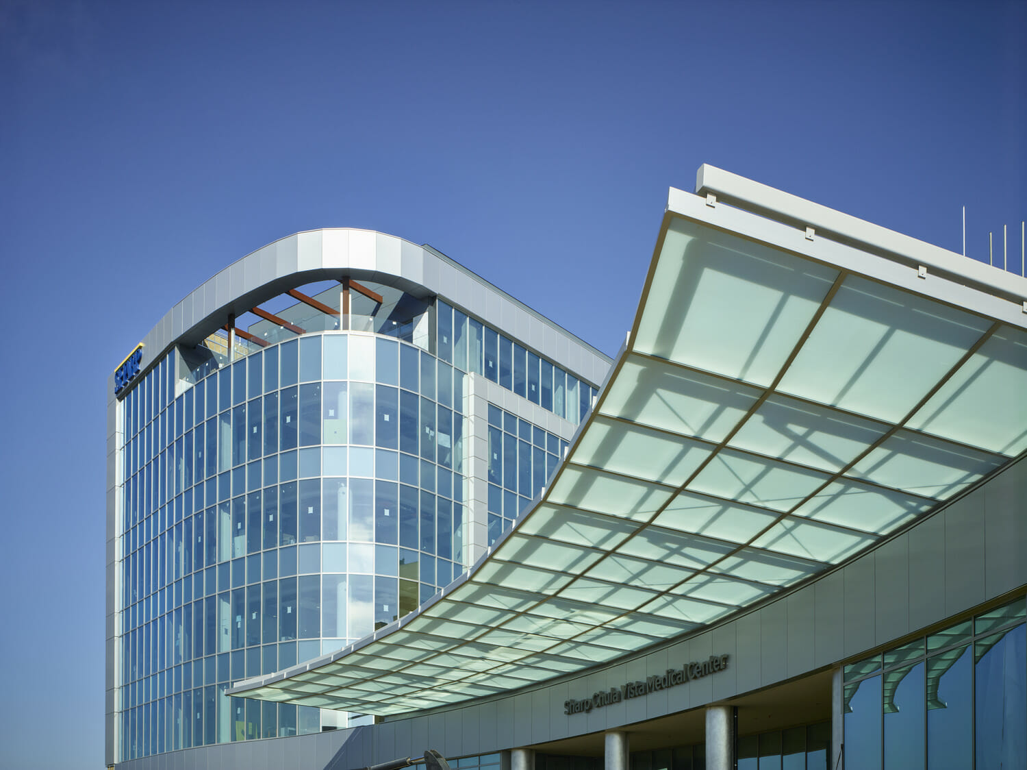 A glass healthcare building with a curved roof.