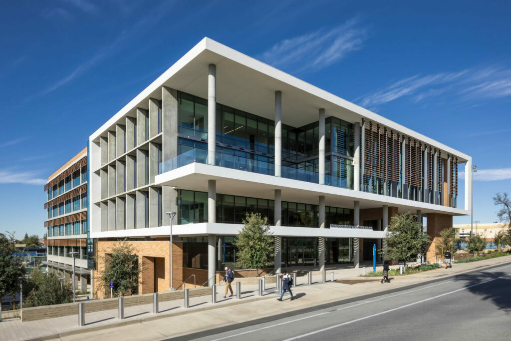 A glass-facade building at the corner of a street.