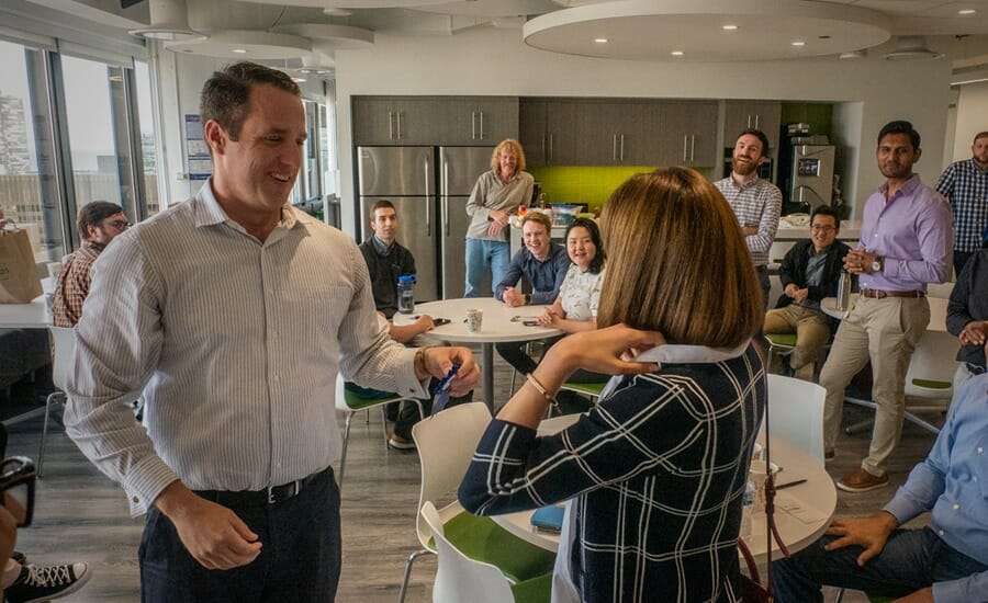 A group of people standing around a table in an office.