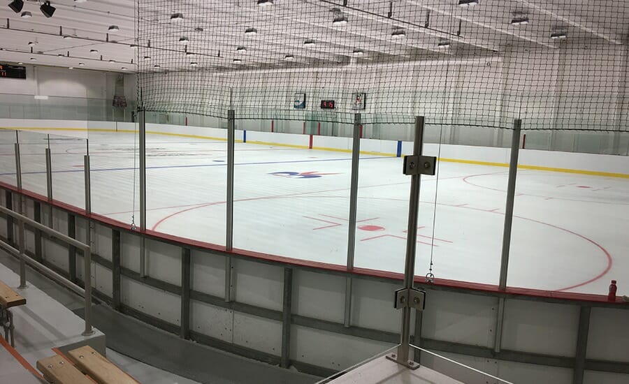 An indoor ice rink with benches and a glass wall.