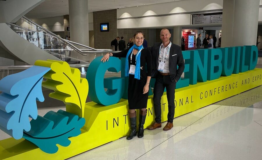Two people standing in front of a greenbuild sign.