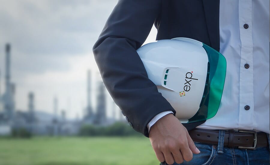 A man wearing a hard hat in front of an oil field.