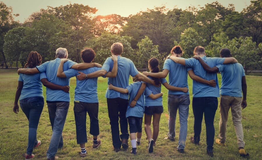 Un groupe de personnes en chemises bleues se tenant ensemble dans un parc.