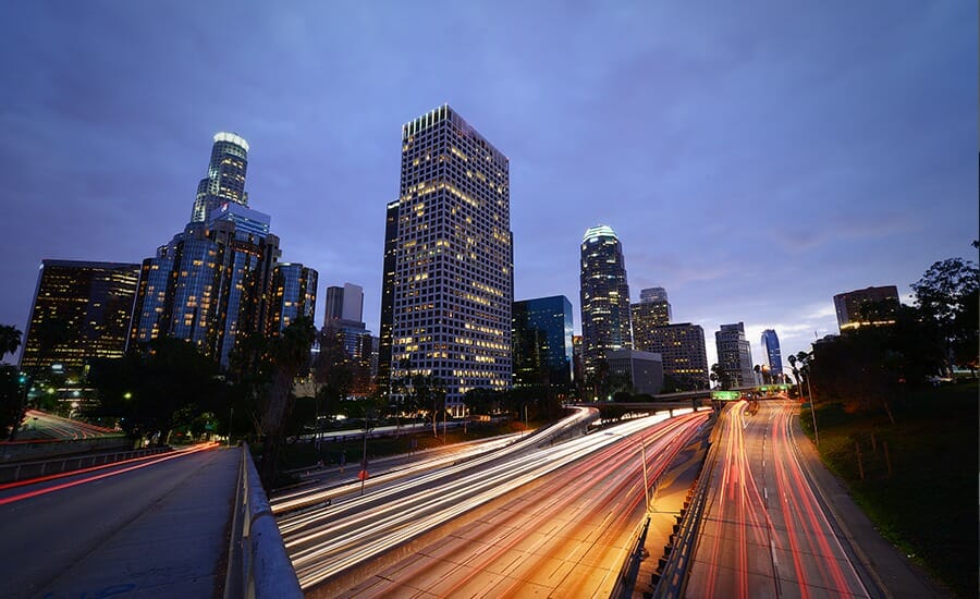 A cityscape at dusk with cars on the road.