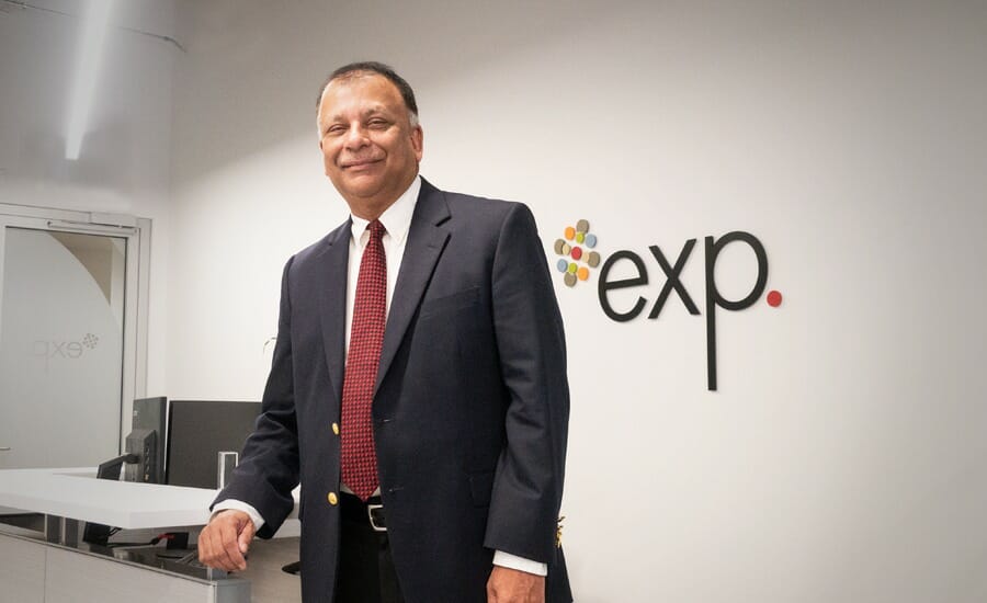 A man in a suit and tie standing in front of an exp sign.