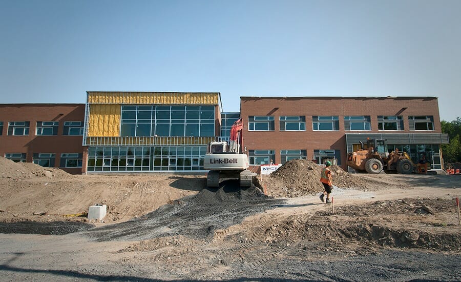 Un chantier de construction avec un bulldozer devant un bâtiment.