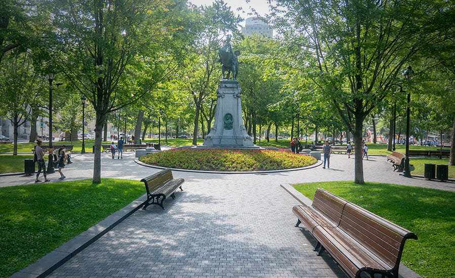 A park with benches and a statue.