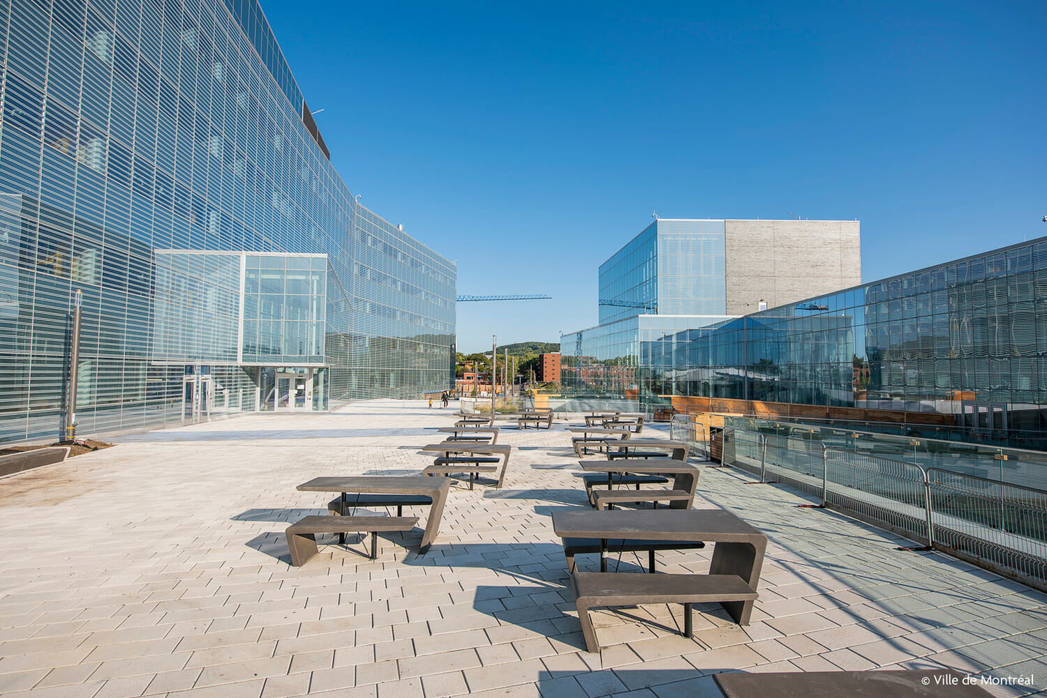 Une passerelle avec des bancs devant un immeuble.