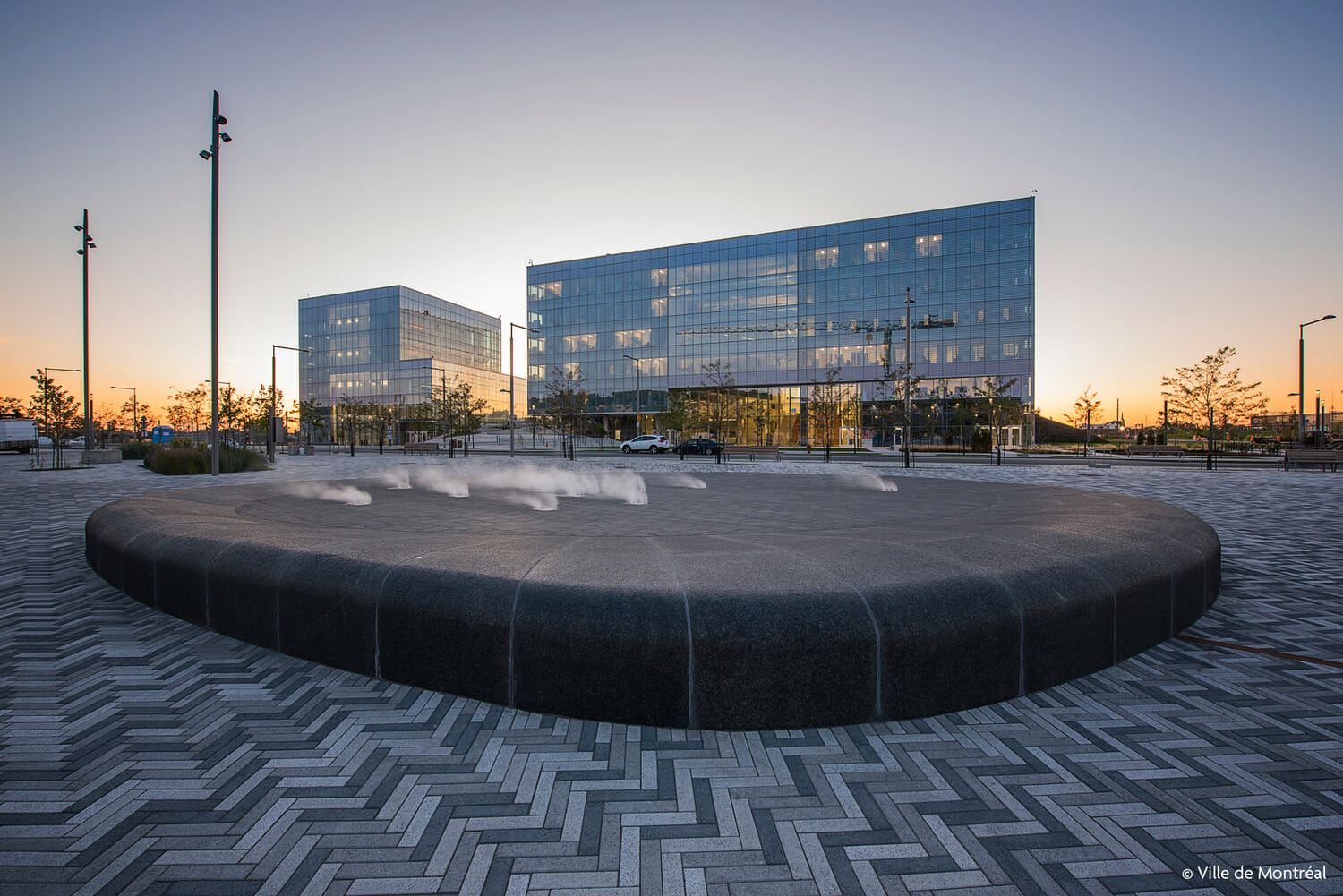 Un banc circulaire devant un bâtiment au crépuscule.