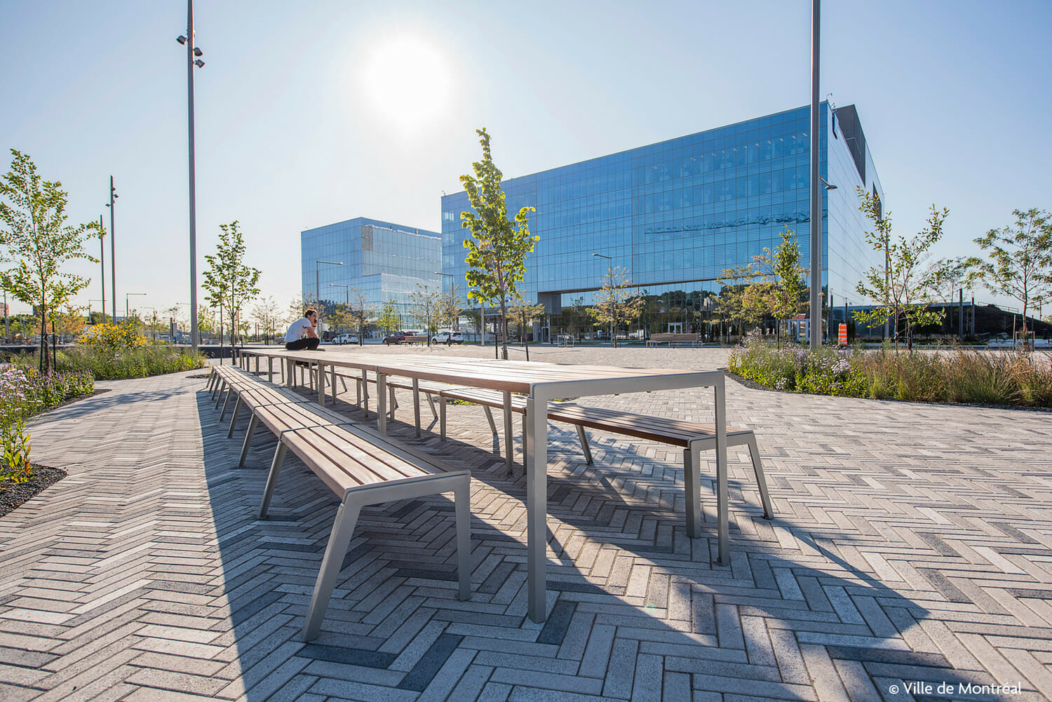 Une personne est assise sur un banc devant un immeuble.