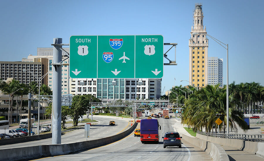 A highway sign with a city in the background.