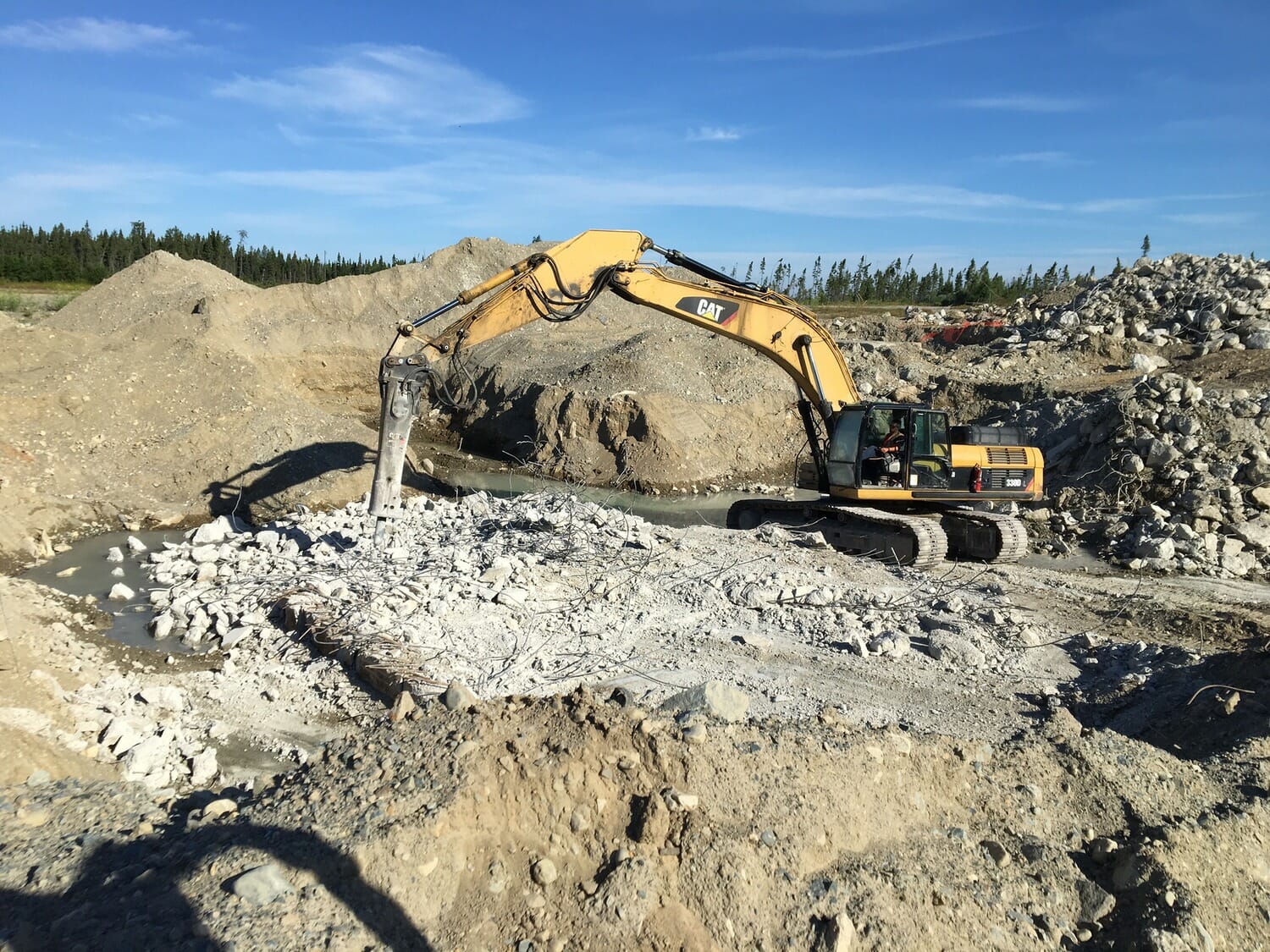 An excavator is working on a pile of rocks.
