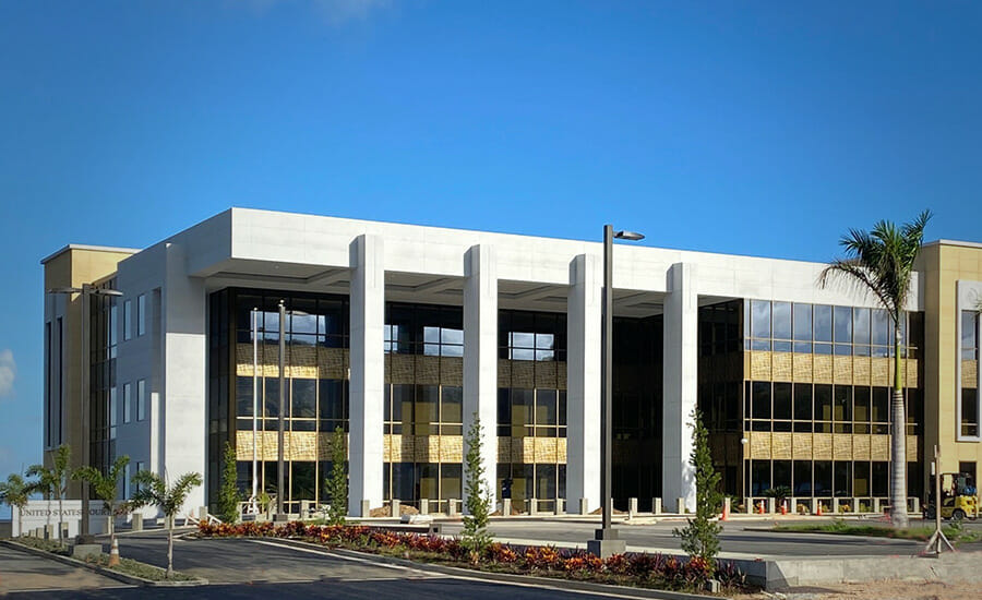 A modern office building with columns and a palm tree.