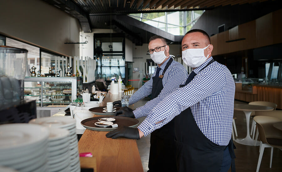 Two men wearing face masks in a restaurant.