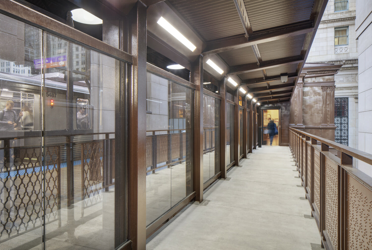 Un couloir avec portes vitrées et garde-corps en verre.