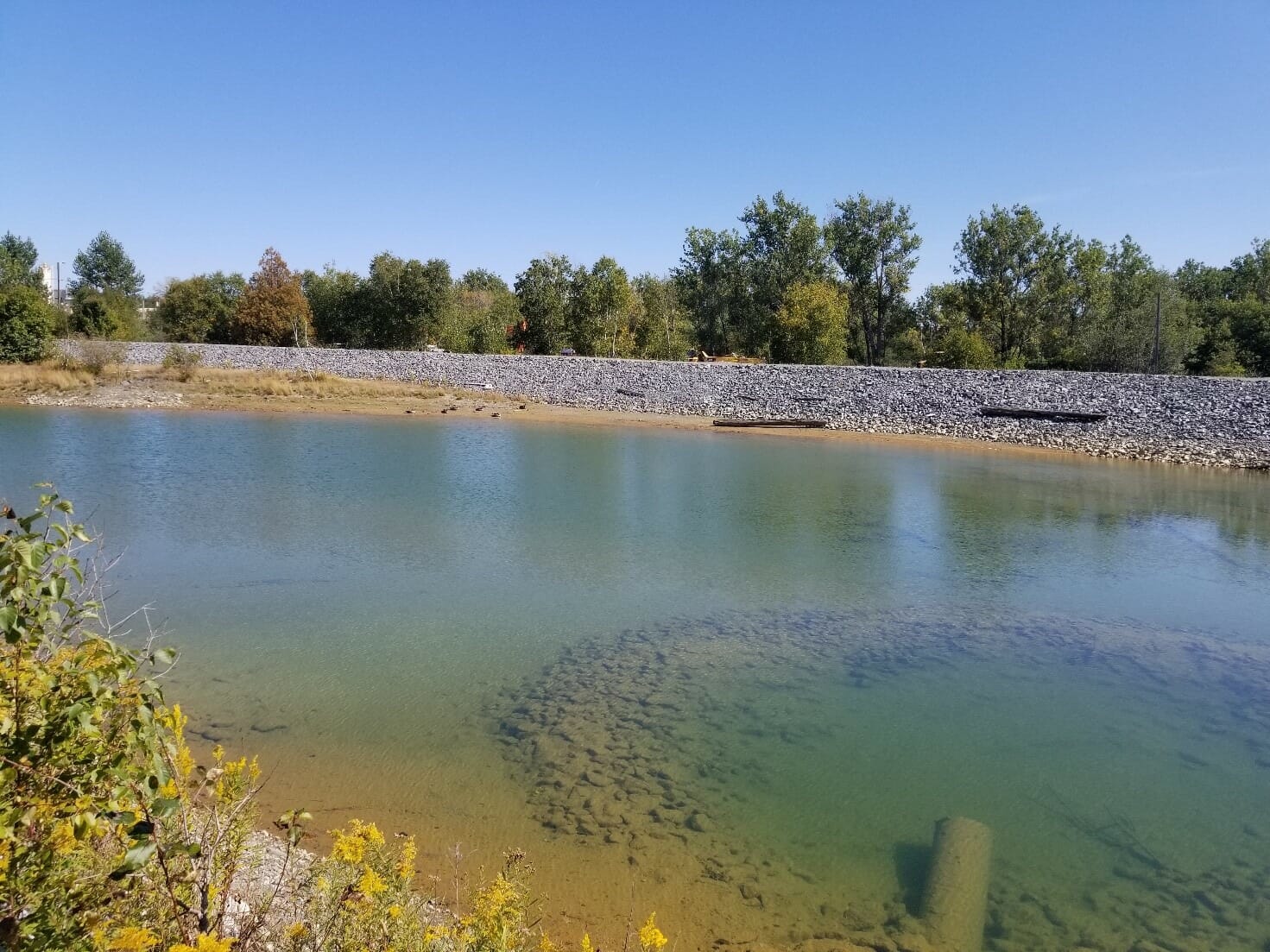 A pond in the middle of a field with rocks around it.