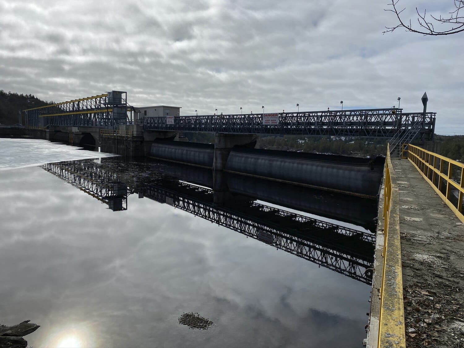 A dam on a lake with a cloudy sky.