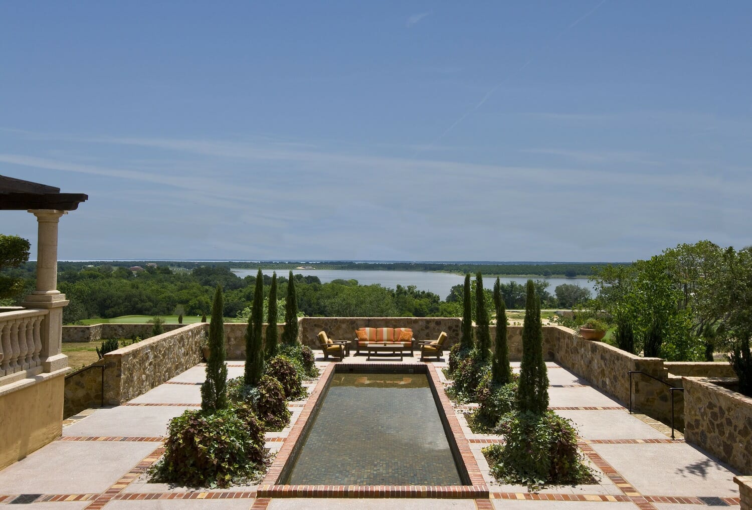 A patio with a fountain and a view of a lake.