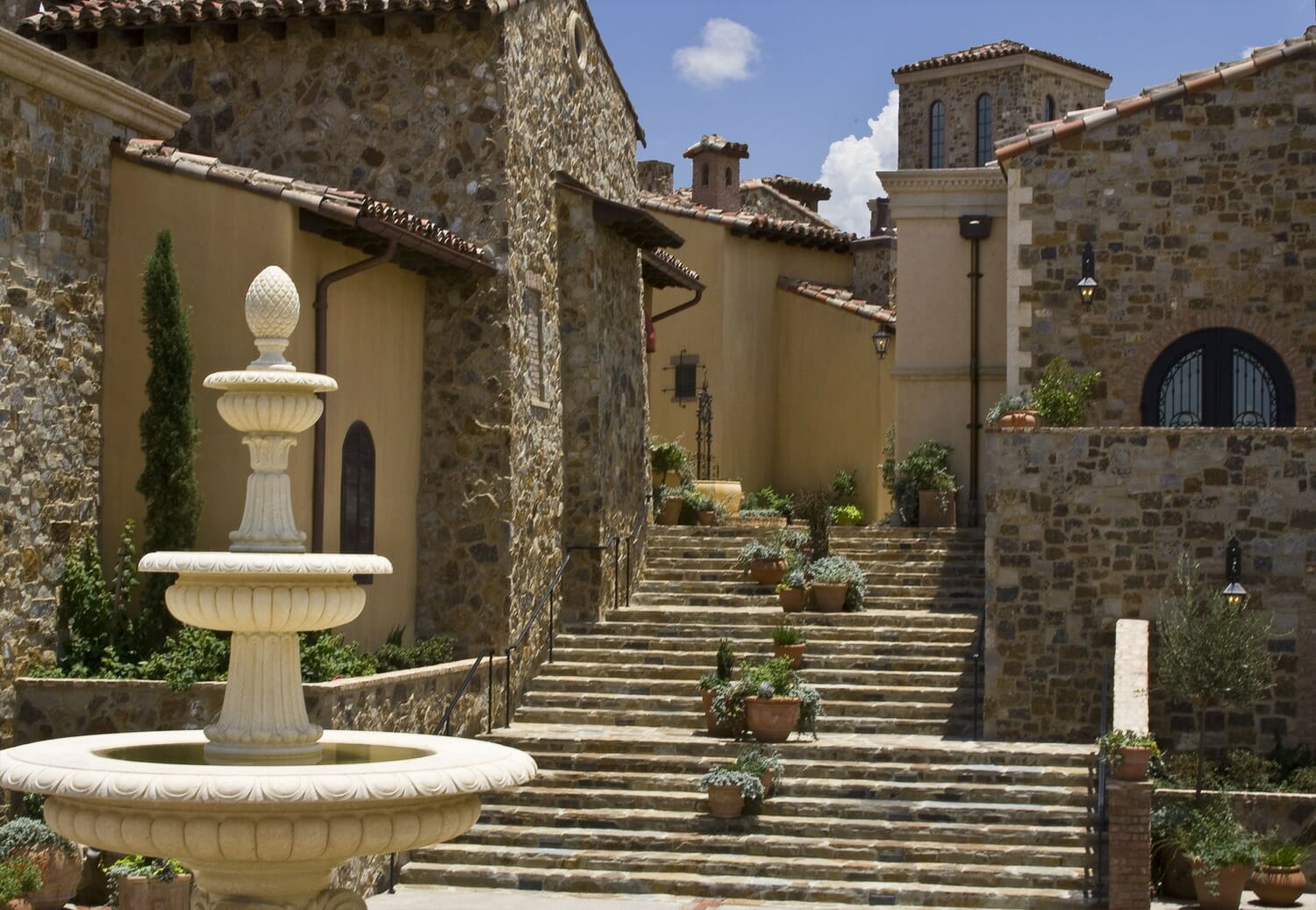 A fountain in front of a stone house.