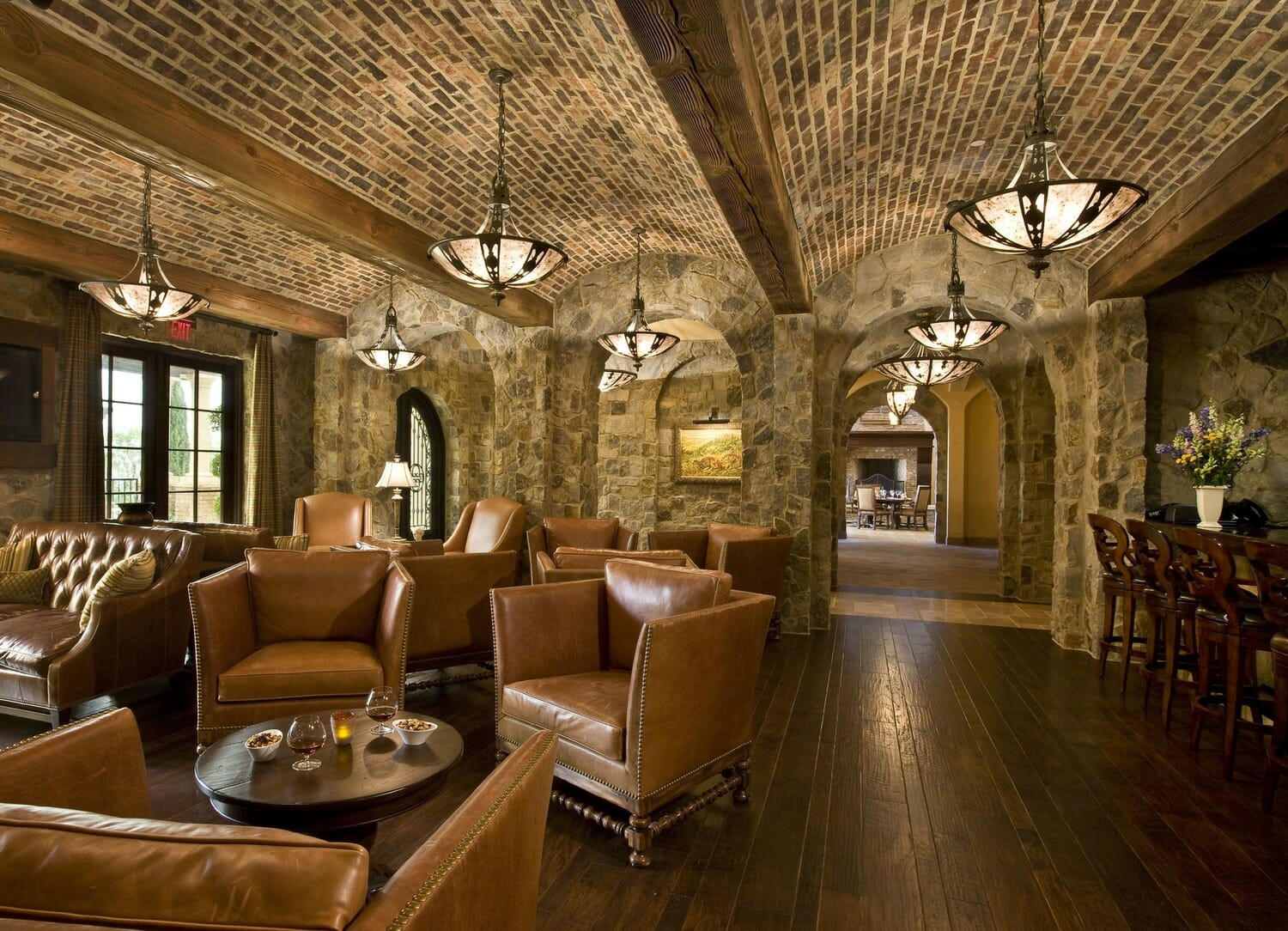 A stone bar with leather chairs and a fireplace.