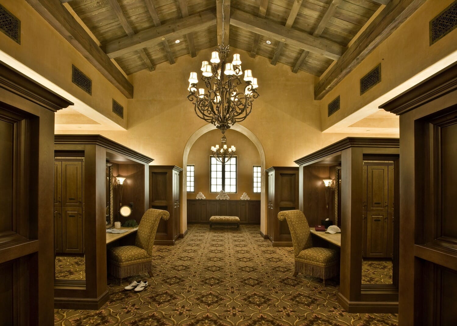 A hallway with a chandelier and chairs.