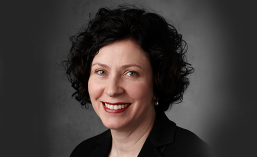 A woman in a black suit smiles for the camera.