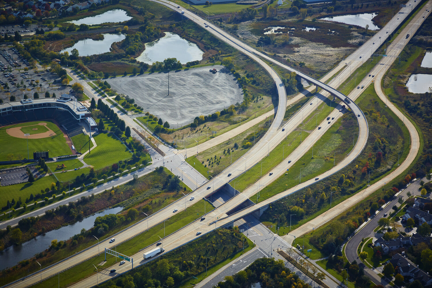 An aerial view of a highway and a baseball field.