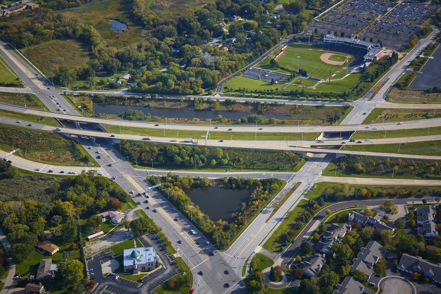 An aerial view of a highway and a baseball field.