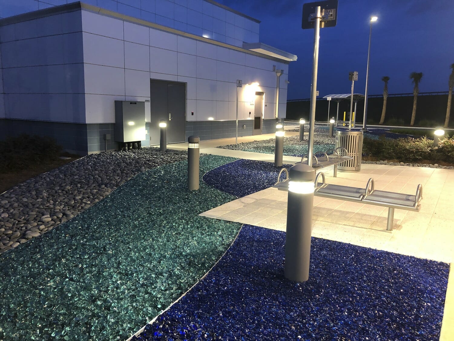 A walkway with a bench and lights at night.