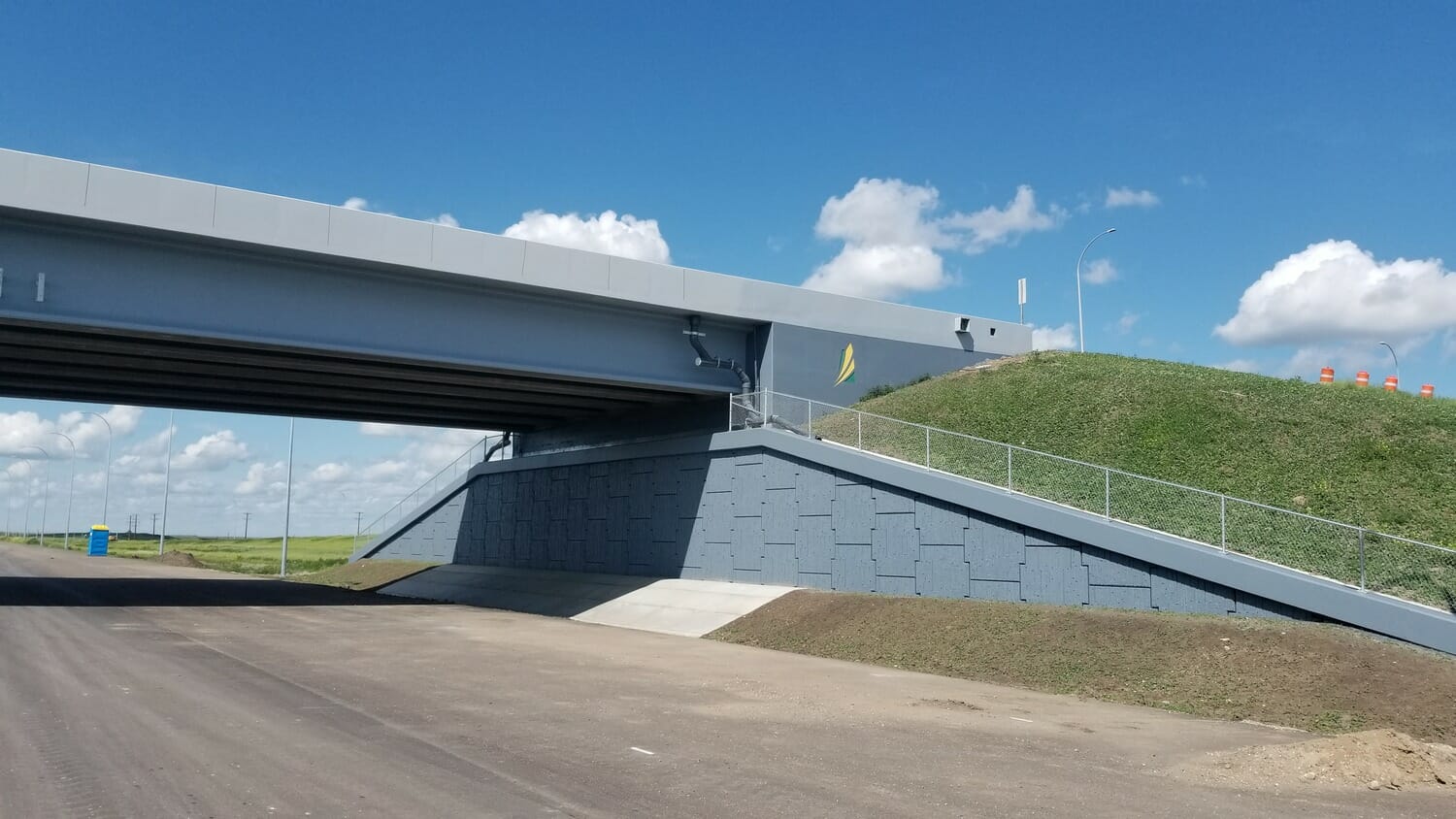 A bridge over a road with a grassy field in the background.