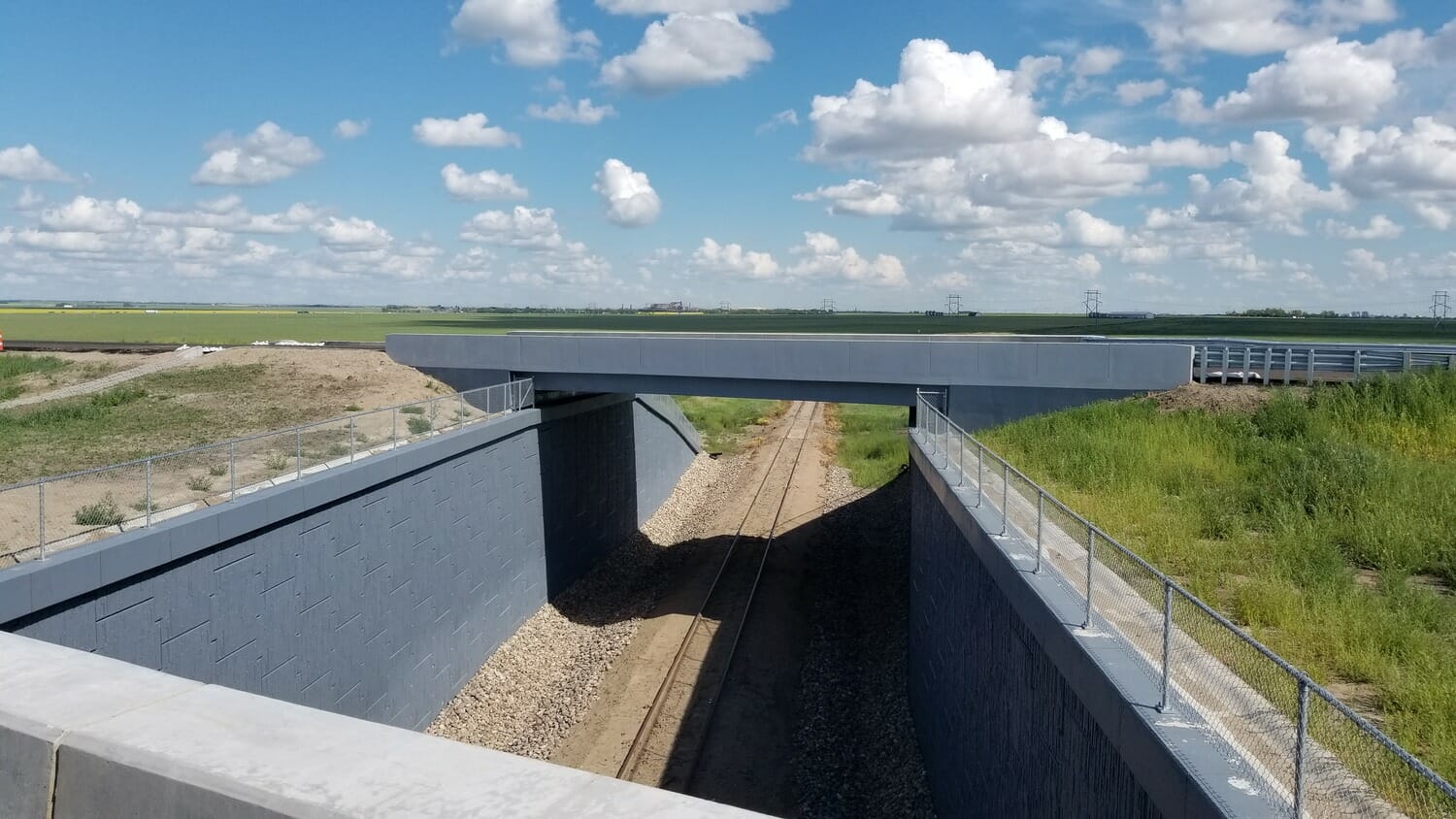 Un pont sur une voie ferrée au milieu d'un champ.